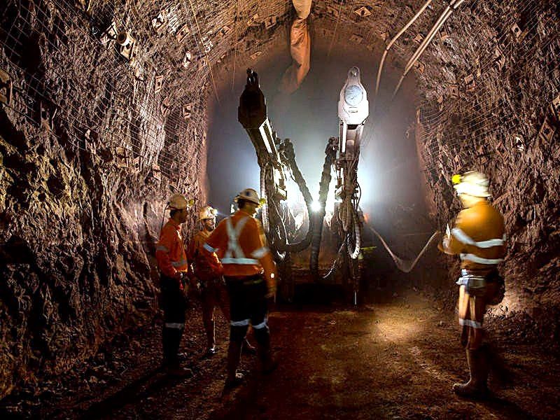 Équipe de travailleurs miniers réunie devant une foreuse dans un tunnel